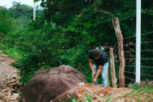 man digging hole near fence line