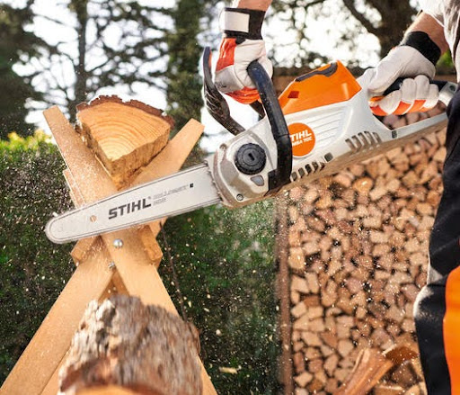 person with white gloves holding chainsaw